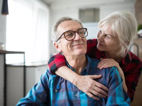 A senior man smiles at his wife as they embrace