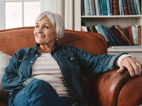 A senior woman sitting on a couch while at home.