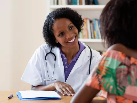 A smiling doctor talking with a female patient. 