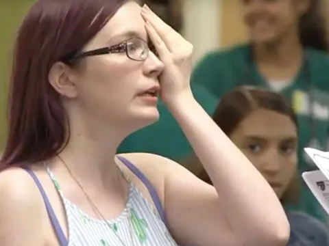 A woman doing an eye test as she covers one of her eyes and reads letters