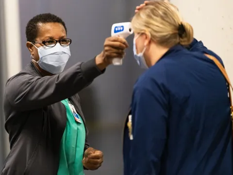 A woman has her temperature checked before a visit.