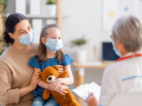 A mother and daughter talking face-to-face with a doctor