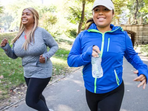 Two women running outside in the fall.