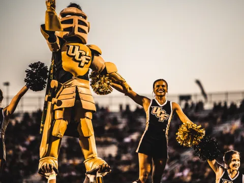 The UCF mascot and cheerleaders during a football game.