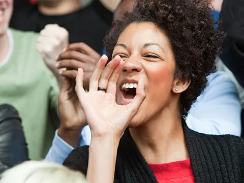 A woman cheers for her team at a sports game.