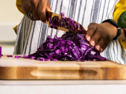 A woman chopping purple cabbage.