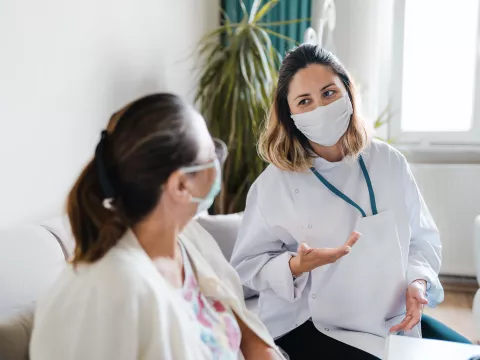 A woman speaking with her doctor wearing a mask.