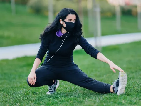 A woman stretching outdoors in the grass.