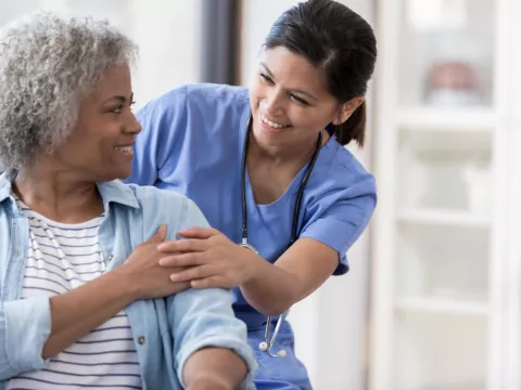 A woman speaks with her nurse after a medical procedure.