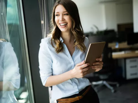 An adult woman smiling next to a window