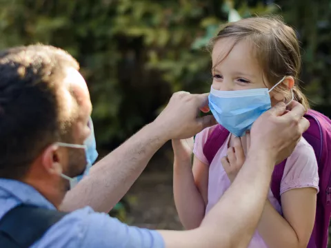 A dad helps his daughter get ready to go back to school.