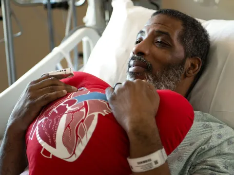 Patient holding heart shaped pillow in patient bed