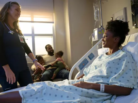 A nurse cares for a patient in a hospital room.