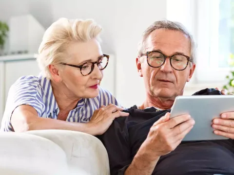 An older couple reading on a tablet.