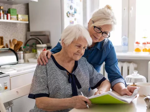 Woman with arm around mother looking at paperwork