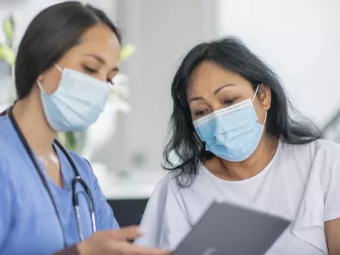 Doctor showing a patient how to schedule an appointment while wearing masks