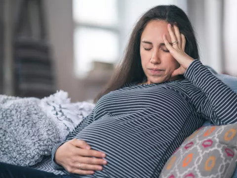 A pregnant woman holds her hand to her stomach.