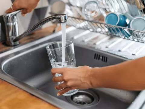 A drinking glass being filled from a tap.