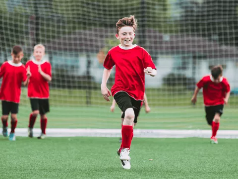 A group of kids in uniforms playing soccer.