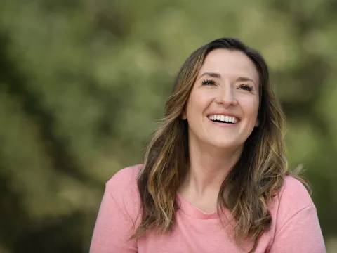 A smiling woman wearing a pink shirt.