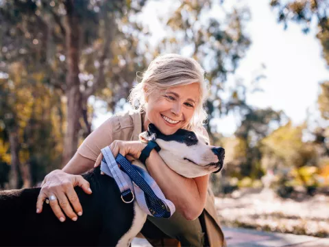 A middle aged woman hugging a dog.