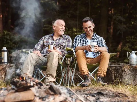 A father and son sitting in front of a campfire