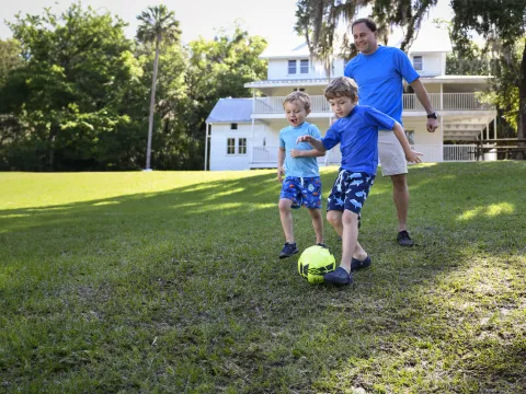 A father playing soccer with his children.