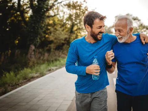 A mid-30s man walking outdoors with his father.