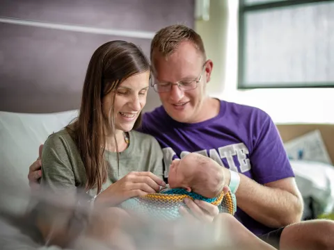 New parents hold their newborn in the hospital.