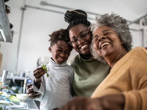 A happy Haitian family cooking together in the kitchen.