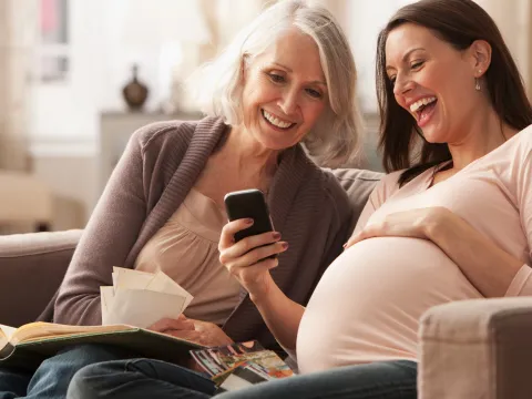 Pregnant Woman Looking at Photos on a Cell Phone with her Mom.