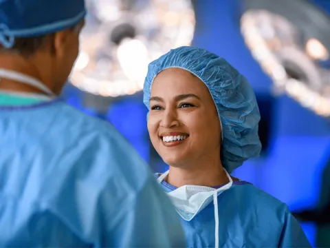 A surgeon smiles at another physician.