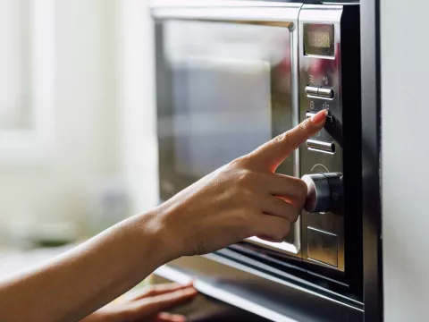 A woman pressing a button of a microwave.