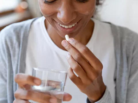 Woman taking a probiotic with a glass of water.