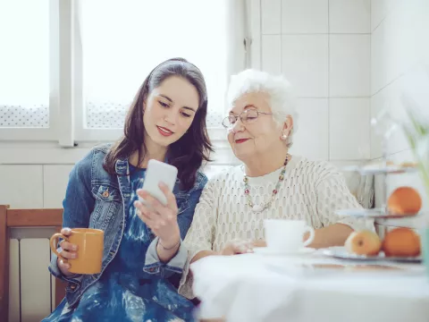 A young woman with an older women checking a cell phone