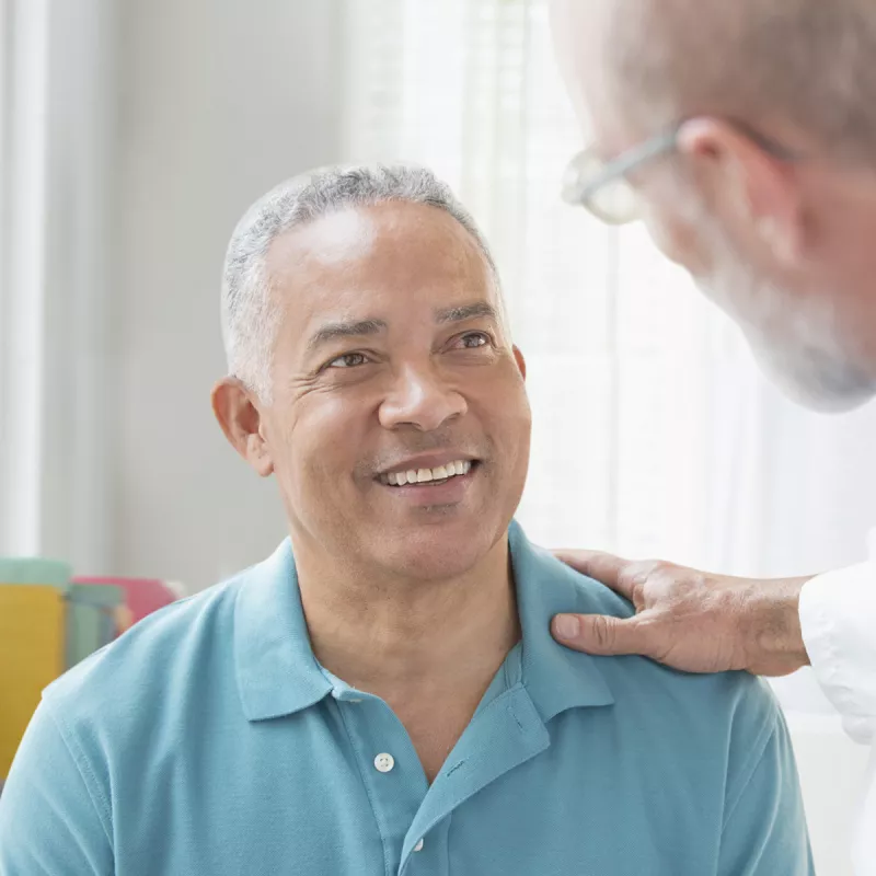 A Caucasian doctor consoles his male patient.