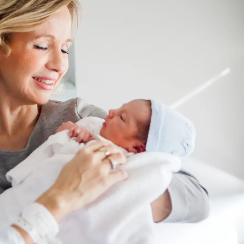 A new grandma visits a newborn in the hospital.