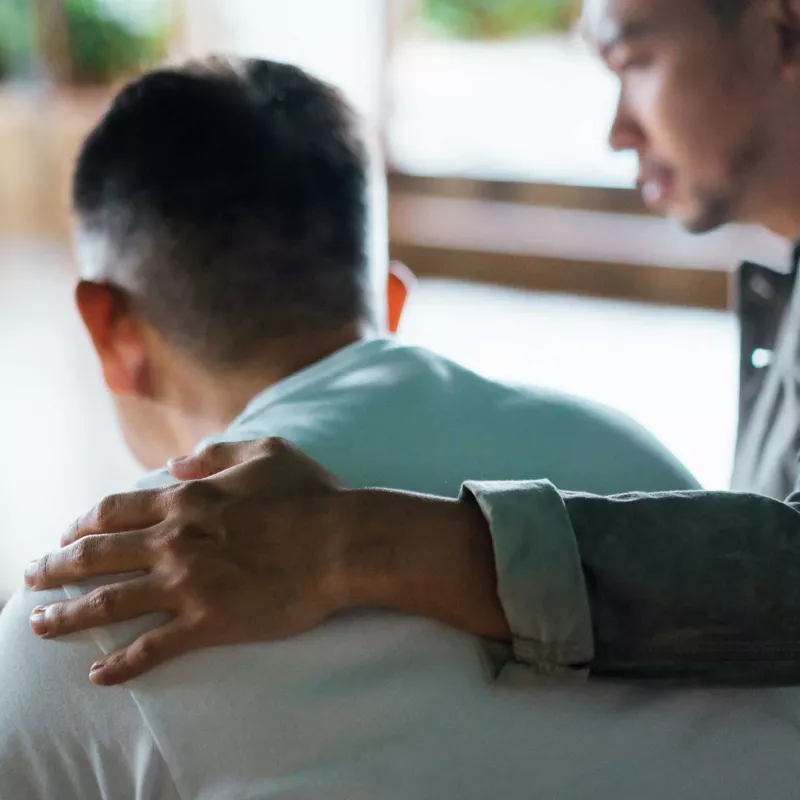 A young man having his arm around a mature man
