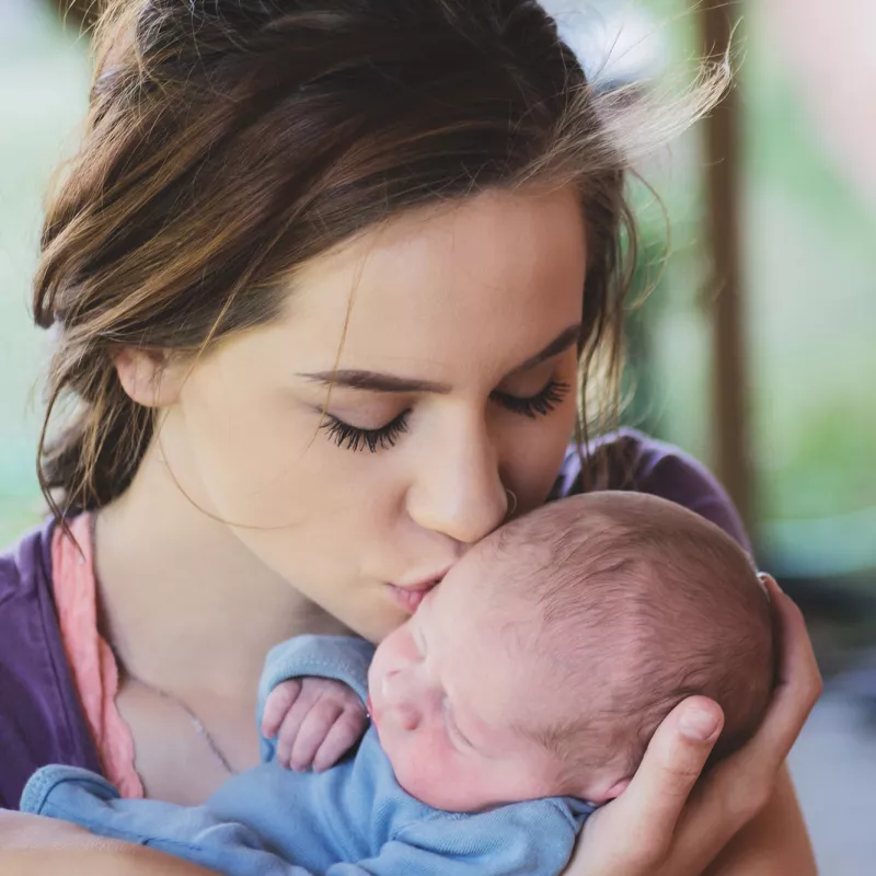 A mom kissing her infant.