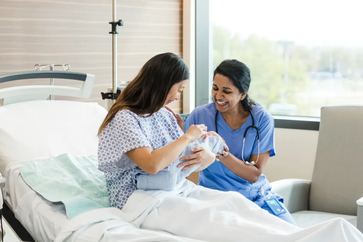 A Patient and a Nurse Laugh and Smile at Her Newborn Baby