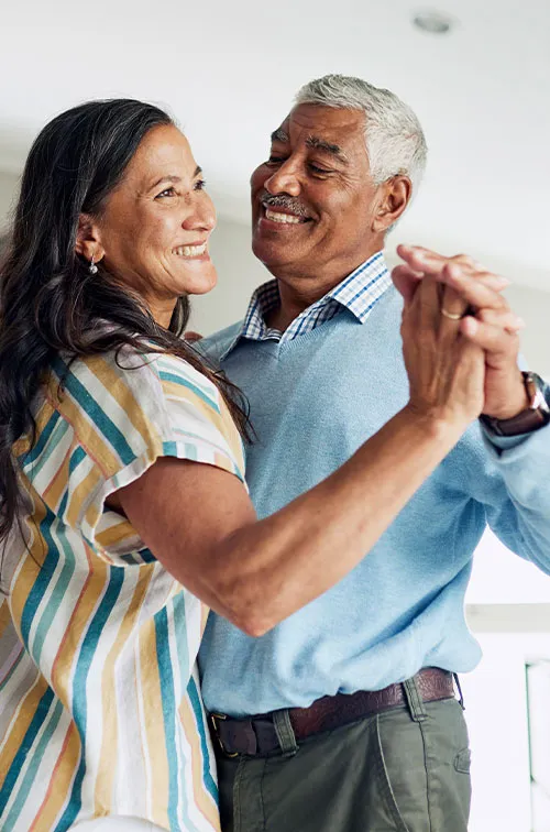 senior couple dancing lively together in living room