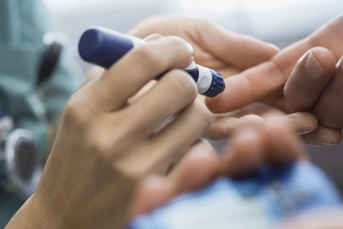 A diabetic patient takes a finger prick reading from an insulin pen.