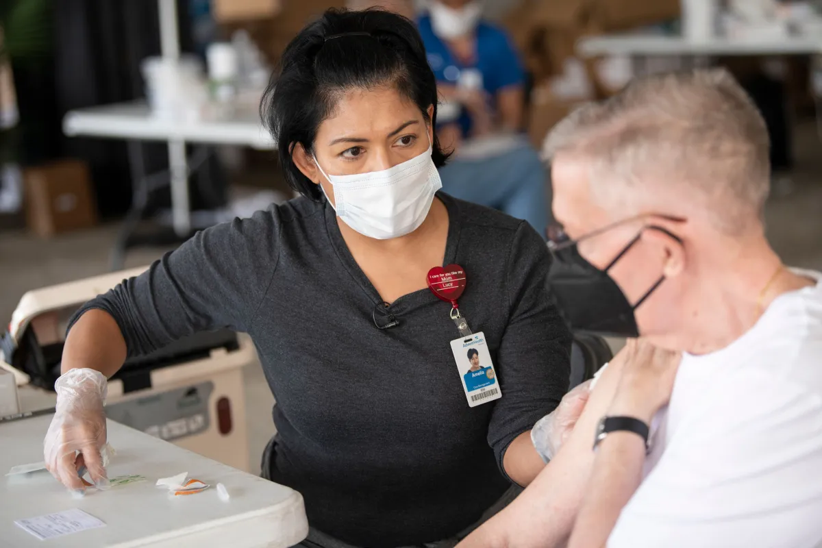 AdventHealth employee talks to an elderly man receiving a coronavirus vaccination