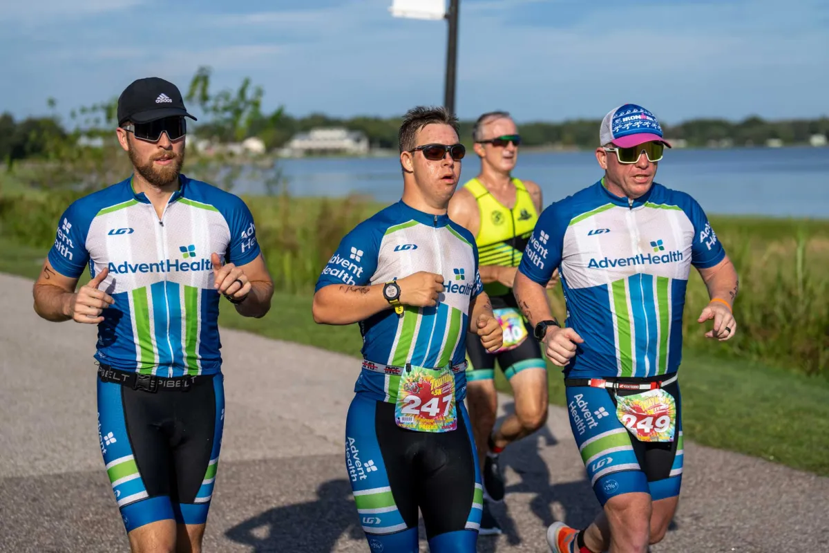 Chris Nikic and his two teammates jogging on a cement trail