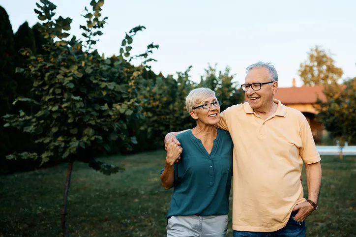 Happy senior couple enjoying while walking embraced in their backyard. 