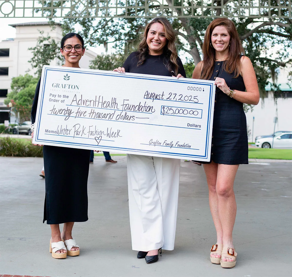 Three people holding a large check
