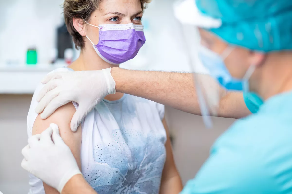 A doctor cleaning a woman's arm before he gives her a shot