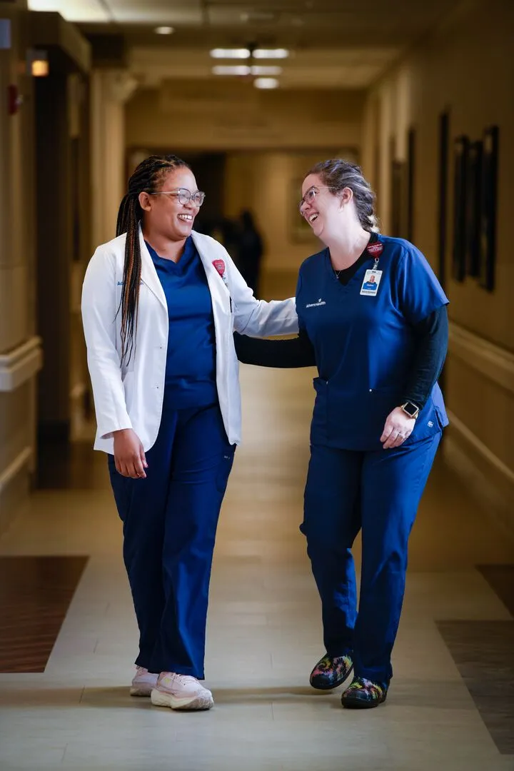 Female doctor and female nurse walk down hospital hallway