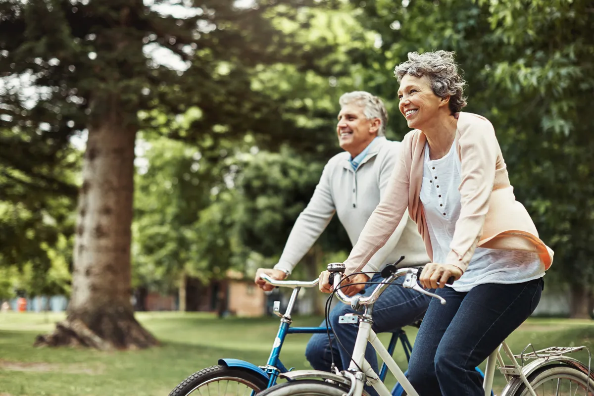 Older couple riding bicycles outdoors.
