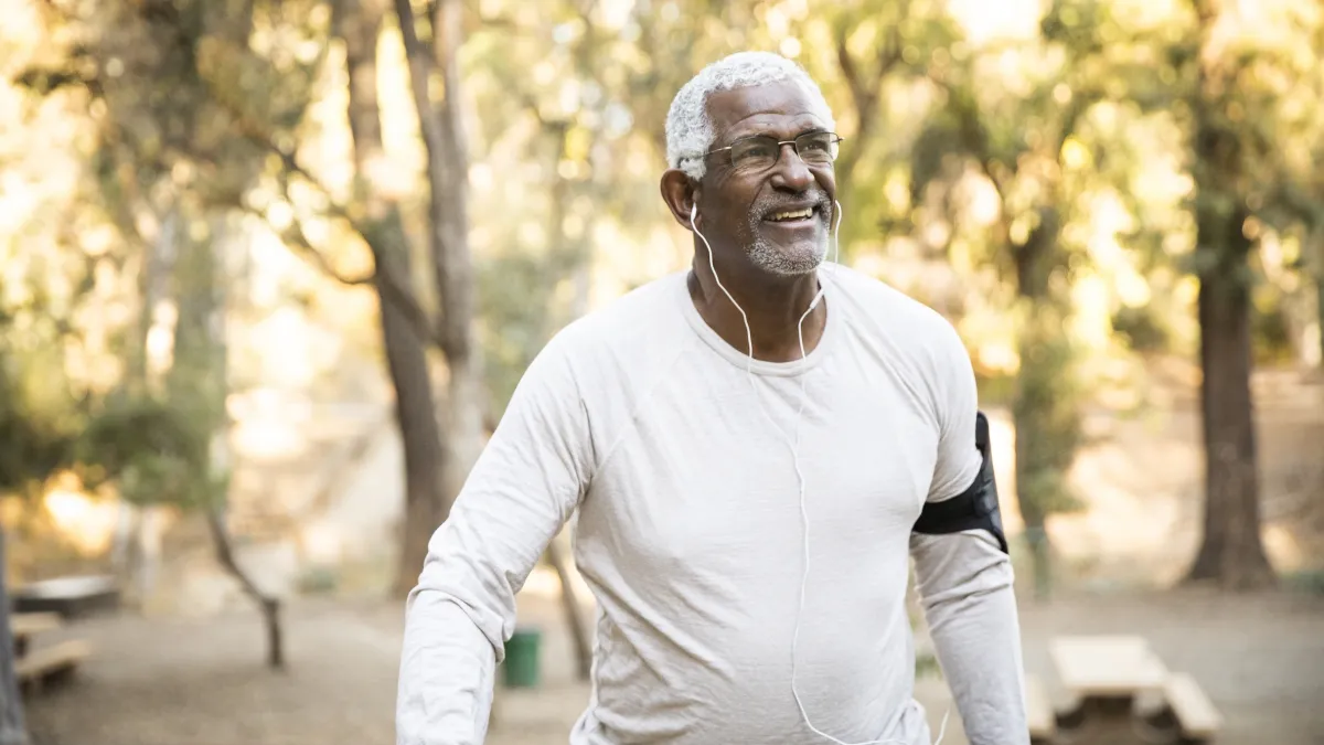 Older African American man walking outdoors.